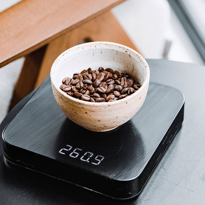Coffee beans in a cup on black coffee scales