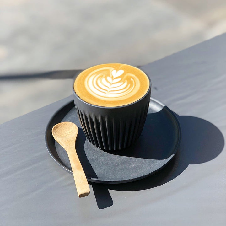 Flat white in reusable coffee cup on table