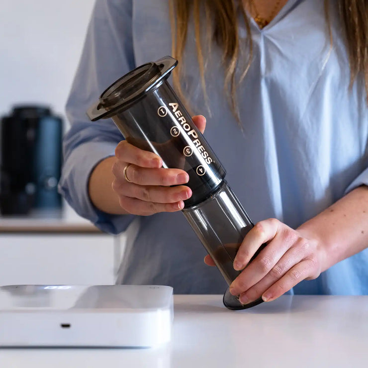 AeroPress being held in hand next to coffee scales